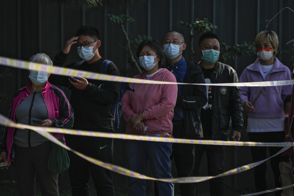 Residents line up behind the caution tape to get their routine COVID-19 throat swabs at a coronavirus testing site in Beijing, Thursday, Oct. 6, 2022. Sprawling Xinjiang is the latest Chinese region to be hit with sweeping COVID-19 travel restrictions, as China further ratchets up control measures ahead of a key Communist Party congress later this month. (AP Photo/Andy Wong)