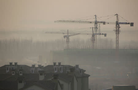 FILE PHOTO: Apartment blocks are pictured next to a construction site on a hazy day in Wuqing district of Tianjin, China, December 10, 2016. To match Exclusive CHINA-GROWTH/ REUTERS/Jason Lee/File Photo