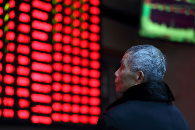 FILE PHOTO: A man looks on in front of an electronic board showing stock information at a brokerage house in Nanjing, Jiangsu province, China February 13, 2019. REUTERS/Stringer