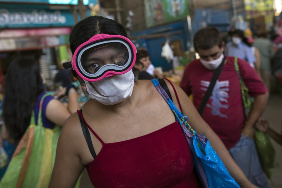 Una mujer usa una máscara quirúrgica y antiparras de buceo en medio de la propagación del nuevo coronavirus mientras compra en un mercado en Lima, Perú, el lunes 23 de marzo de 2020. (AP Foto / Rodrigo Abd)