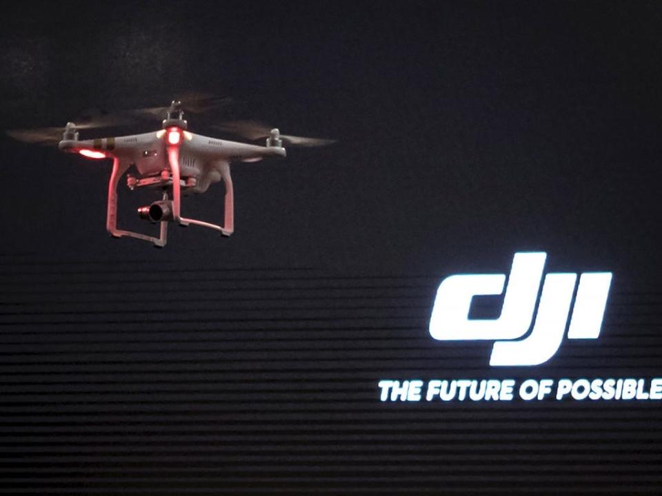 A drone flies in front of a logo that reads "DJI, the future of possible."