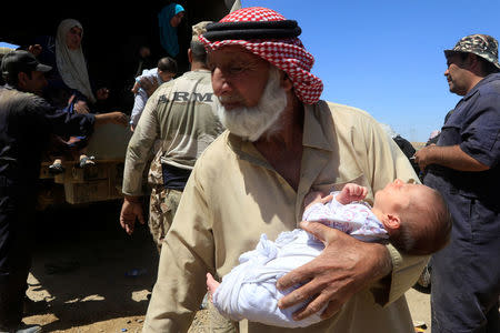 A displaced Iraqi man who fled his home holds a child during a battle between Iraqi forces and Islamic State militants in western Mosul, Iraq May 17, 2017. REUTERS/Alaa Al-Marjani