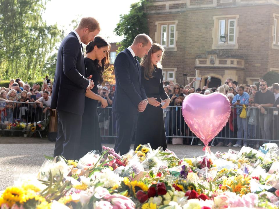 Prince Harry, Meghan Markle, Prince William, and Princess Kate look at flowers at Windsor Castle.