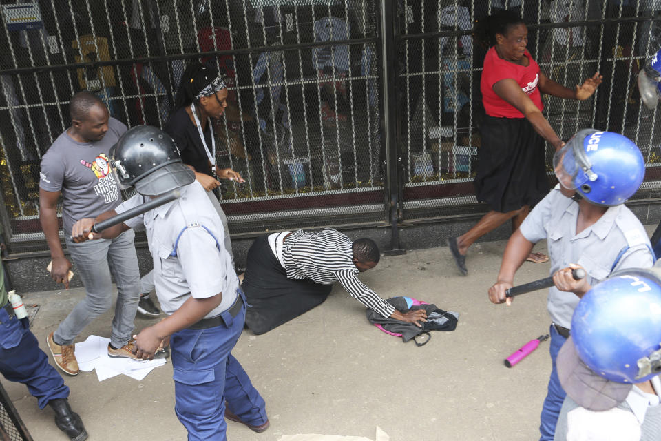 Police surround opposition party supporters who had gathered to hear a speech by the country's top opposition leader in Harare, Wednesday, Nov. 20, 2019. Zimbabwean police with riot gear fired tear gas and struck people who had gathered at the opposition party headquarters to hear a speech by the main opposition leader Nelson Chamisa who still disputes his narrow loss to Zimbabwean President Emmerson Mnangagwa. (AP Photo/Tsvangirayi Mukwazhi)