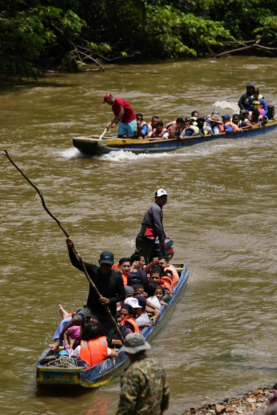 Migrants heading north arrive to Lajas Blancas, Darien province, Panama, Friday, Oct. 6, 2023, after walking across the Darien Gap from Colombia. Below is a Panamanian border police officer. (AP Photo/Arnulfo Franco)