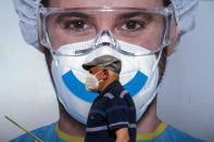 A man wearing face mask walks past an advertising of a private clinic in Barcelona, Spain on Monday Aug. 31, 2020. Spain, with nearly 440,000 infections of the new virus since February, has become western Europe's hardest hit country by a new surging wave of fresh outbreaks. (AP Photo/Emilio Morenatti)