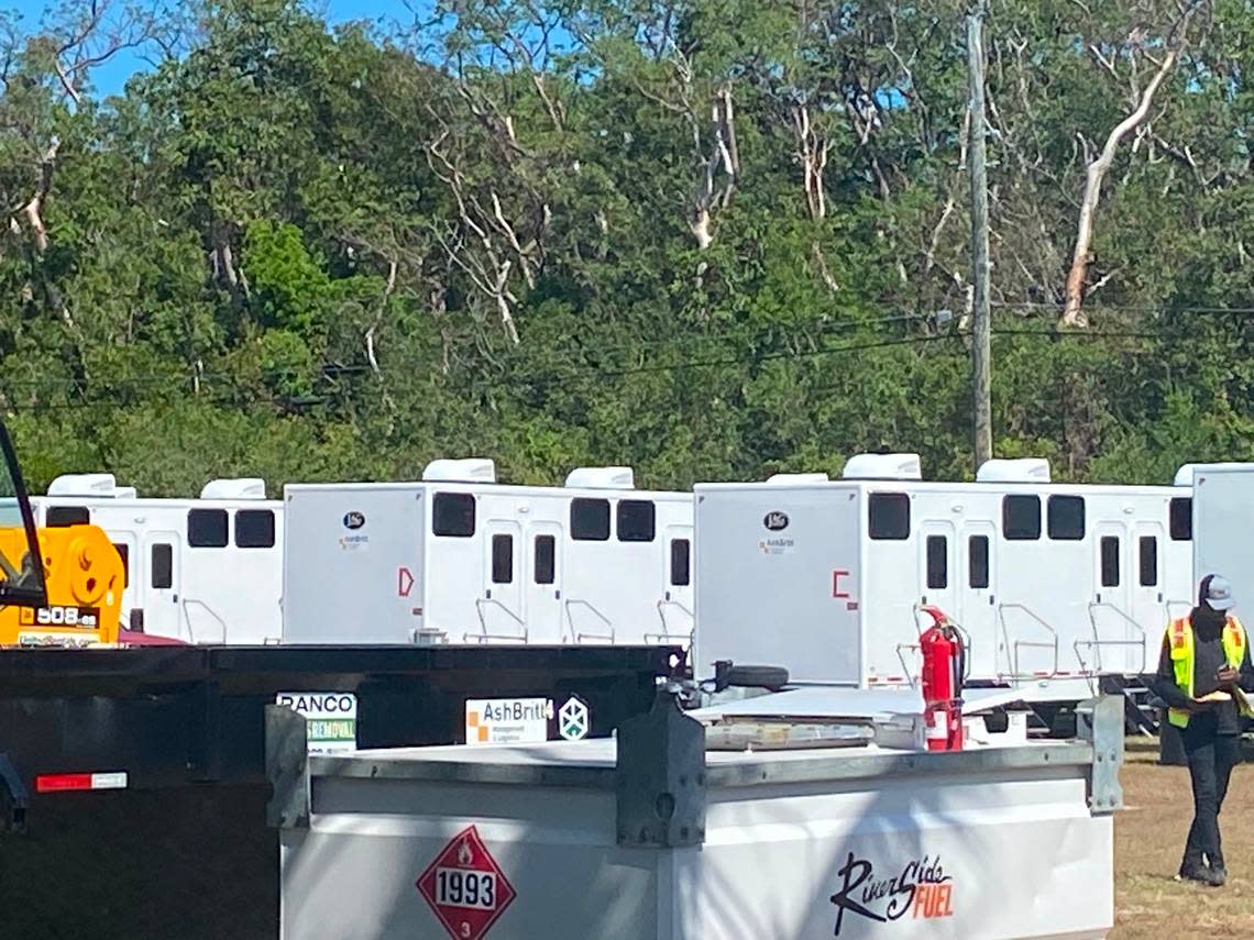 A worker walks past a row of trailers located on a lot on Aregood Lane on Plantation Key in the Florida Keys Thursday, Feb. 16, 2023. The trailers are part of a state base camp to house police officers sent to the Keys to help with an increase in maritime migration from Cuba and Haiti, according to a statement from the Village of Islamorada.