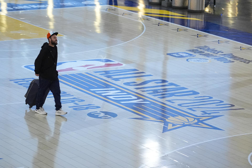 Travelers using Indianapolis International Airport make their way across a replica of the court that will be use for the NBA All-Star game Thursday, Jan. 18, 2024. Authorities have created a full-size replica basketball court with two baskets, one equipped with a short clock, to promote Indy's first All-Star Game since 1984. (AP Photo/Michael Conroy)