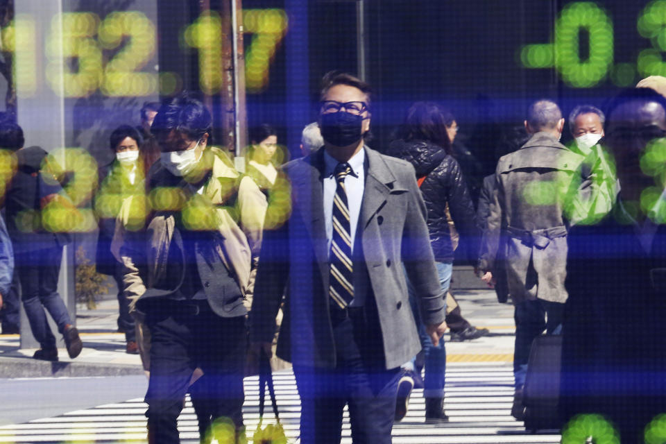 FILE - In this March 18, 2020, file photo, people are reflected on the electronic board of a securities firm in Tokyo. Japan's economic growth plunged into recession in the first quarter as the coronavirus pandemic squelched production, exports and spending, and fears are growing worse times may lie ahead, according to a report on Monday, May 18, 2020. (AP Photo/Koji Sasahara, File)