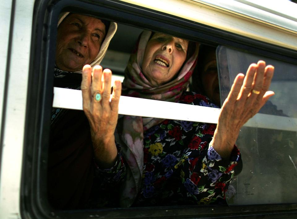 A woman gestures from a van carrying displaced people, one of thousands of civilians fleeing their southern villages as a forty eight hour halt of the Israeli bombing campaign allows access out of the area July 31, 2006 in Tyre, Lebanon.&nbsp;