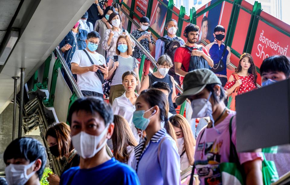 TOPSHOT - People with face masks arrive at a BTS Sky train station in Bangkok on January 27, 2020. - Thailand has detected eight Coronavirus cases so far -- three of whom are receiving treatment in hospital and five of whom have been discharged, according to a statement from Health Minister Anutin Charnvirakul: (Photo by MLADEN ANTONOV/AFP via Getty Images)