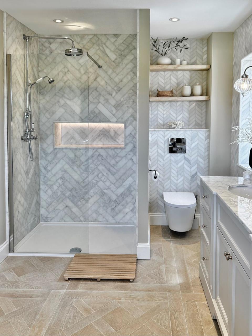 shower with herringbone grey tiles, a matching shower niche and wooden parquet