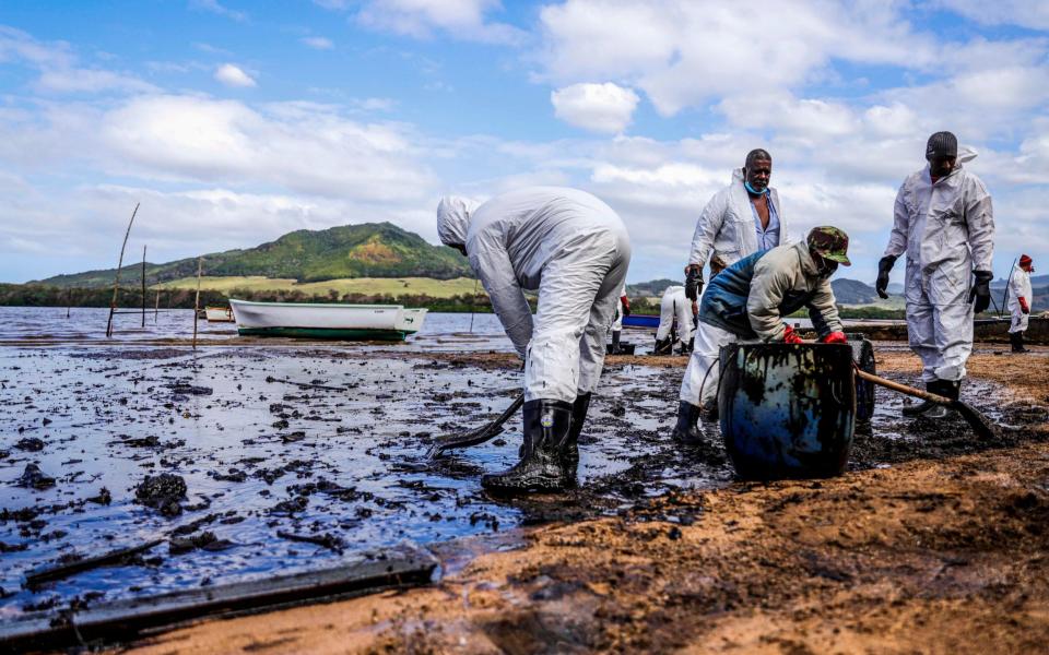 People scoop leaked oil from the vessel MV Wakashio, belonging to a Japanese company but Panamanian-flagged, that ran aground and caused oil leakage near Blue bay Marine Park in southeast Mauritius on August 9, 2020. -  - DAREN MAUREE /AFP