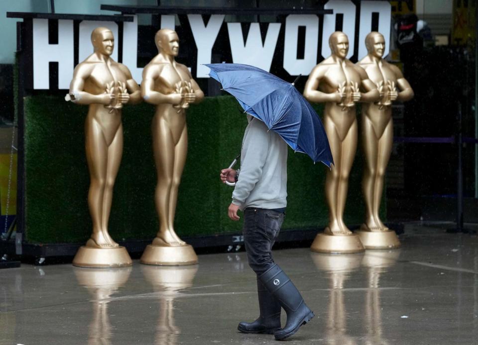 PHOTO: A pedestrian shields himself from strong winds and rain on Hollywood Boulevard during Tropical Storm Hilary, Sunday, Aug. 20, 2023, in Los Angeles. (Chris Pizzello/AP)