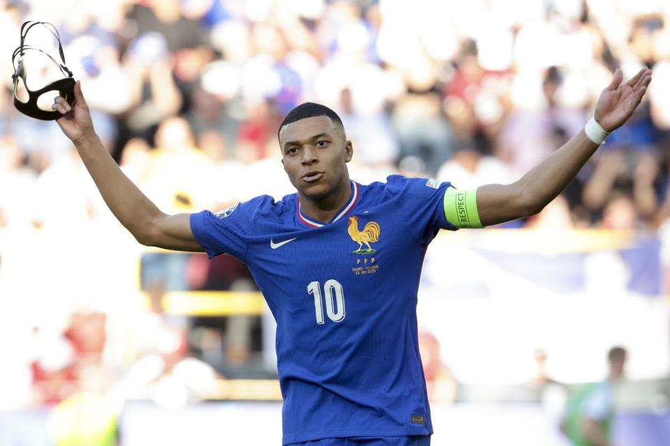 kylian mbappe holds a protective face mask in his right hand as he celebrates a goal for france