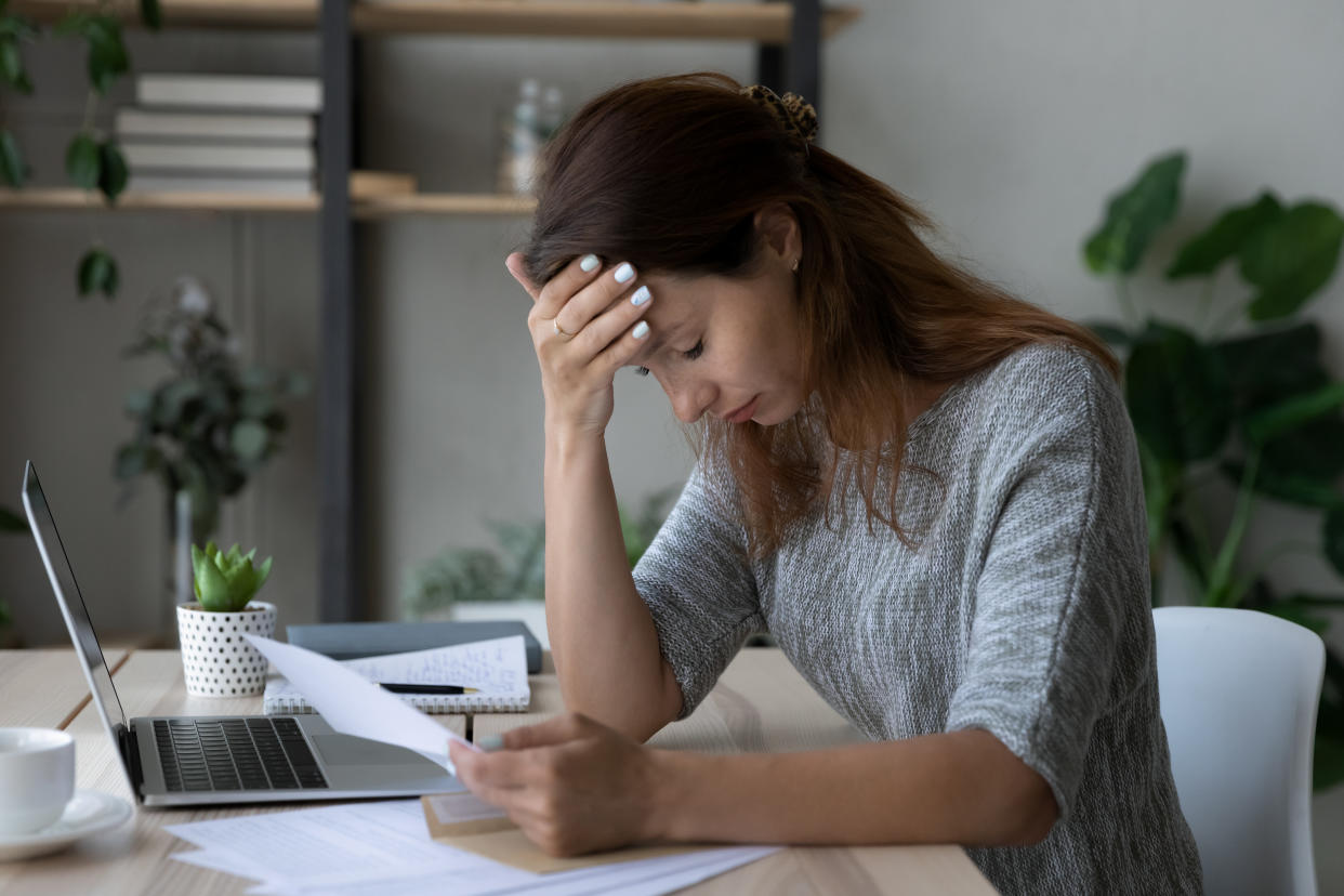 Depressed young woman holding paper document, stressed by getting bank debt notification or eviction letter having financial problems. Unhappy female student received entrance exams failure results.