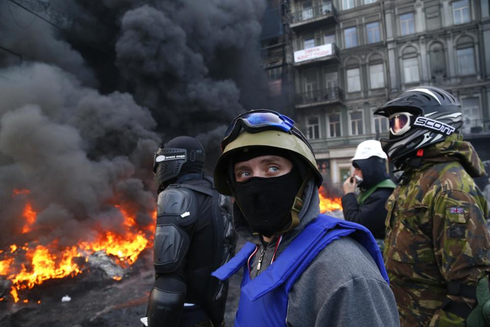 Manifestantes detrás de las barricadas frente a la policía antimotines en Kiev. Ucrania, el sábado 25 de enero de 2014. El Ministerio del Interior de Ucrania ha acusado a los manifestantes de capturar a dos policías en momentos que los enfrentamientos violentos se renudan. (Foto AP/Serguei Grits)