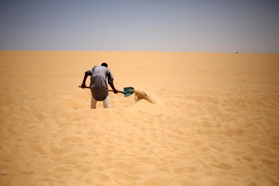 A worker digs fresh holes in the sand for patients who will take sand baths in Siwa, Egypt, August 13, 2015. (REUTERS/Asmaa Waguih)