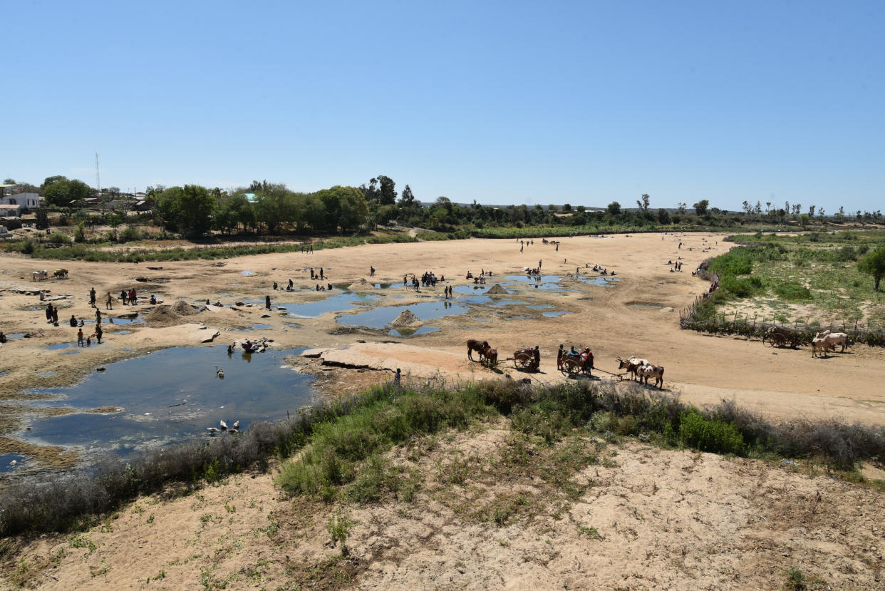 People gather at holes dug to access water.