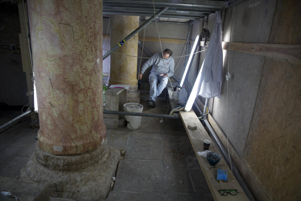 In this Thursday, Dec. 6, 2018 photo, a restoration expert works on a granite column inside the Church of the Nativity, built atop the site where Christians believe Jesus Christ was born, in the West Bank City of Bethlehem. The renovation is lifting spirits in the biblical town of Bethlehem ahead of Christmas, offering visitors a look at ancient mosaics and columns that have been restored to their original glory for the first time in 600 years. (AP Photo/Majdi Mohammed)