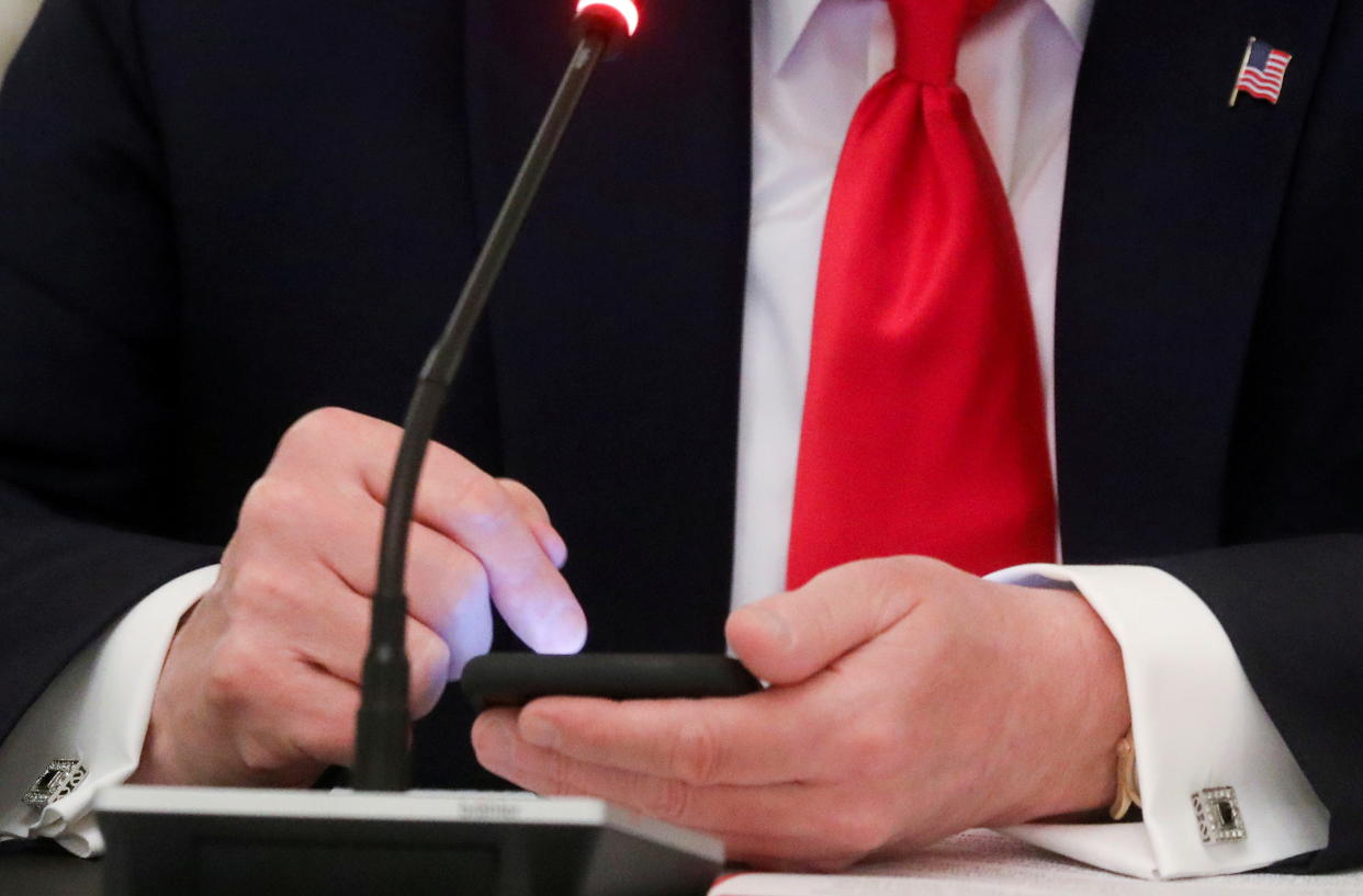 U.S. President Donald Trump taps the screen on a mobile phone in the State Dining Room at the White House in Washington, U.S., June 18, 2020. (Leah Millis/Reuters)