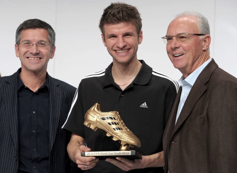 Professional soccer player Thomas Mueller (M) poses with the Golden Shoe for top scorer at the FIFA World Cup 2010 Awards ceremony in Herzogenaurach next to Adidas boss Herbert Hainer (L) and soccer icon Franz Beckenbauer. Bayern Munich midfielder Thomas Mueller said he will resume the Bundesliga season against Hoffenheim on 12 January with "mixed feelings" after the death of club icon Franz Beckenbauer. David Ebener/dpa