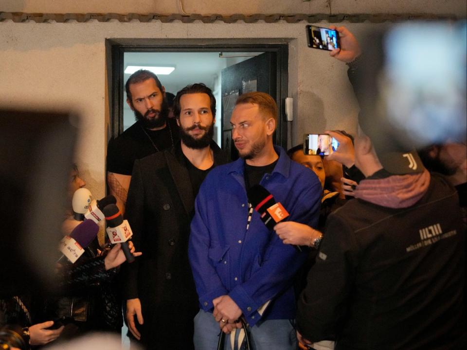 Andrew Tate, left, and his brother Tristan stand outside a police detention facility in Bucharest, Romania (AP)