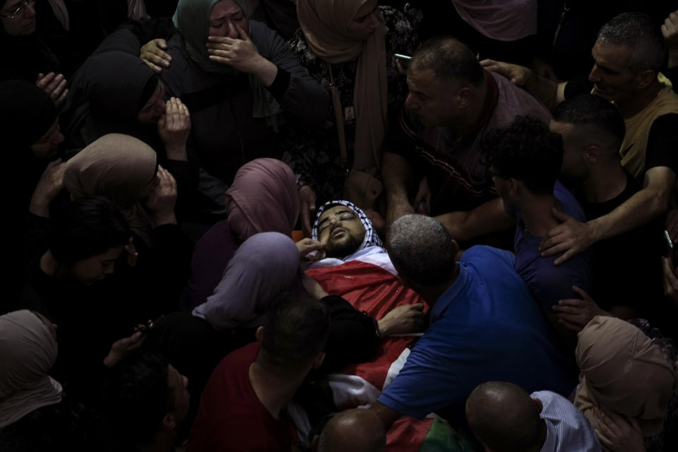 Dolientes palestinos alrededor del cadáver de Fayez Damdoum durante su funeral en la aldea de Azariyah, en Cisjordania, el 1 de octubre de 2022. La policía fronteriza paramilitar de Israel dijo que sus fuerzas le dispararon al hombre, alegando que intentó arrojarles una bomba incendiaria cuando acudían a dispersar una manifestación. El Ministerio de Salud palestino identificó al joven muerto como Fayez Damdoum, de 18 años. (AP Foto/Mahmoud Illean)