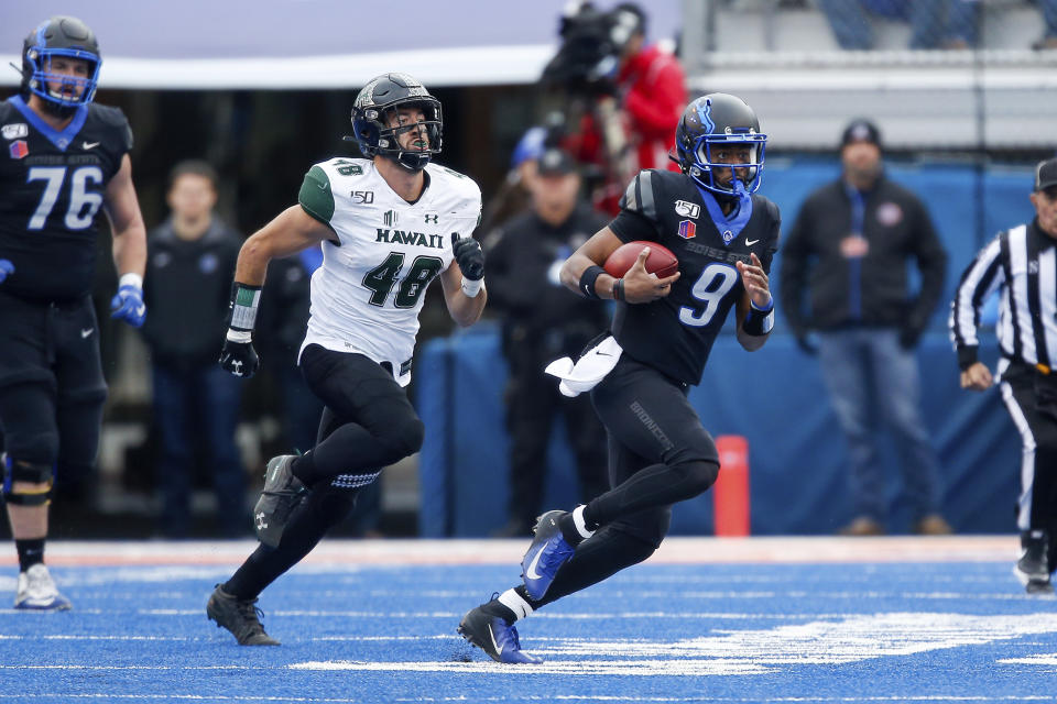 Boise State quarterback Jaylon Henderson, right, scrambles away from Hawaii defensive lineman Derek Thomas, left, during the first half of an NCAA college football game for the Mountain West Championship Saturday, Dec. 7, 2019, in Boise, Idaho. (AP Photo/Steve Conner)
