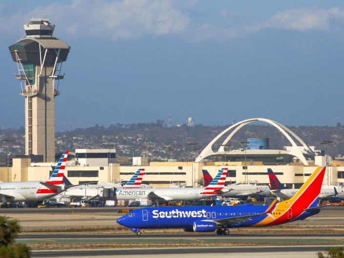 A Southwest Airlines plane lands at Los Angeles International Airport next to American Airlines planes.