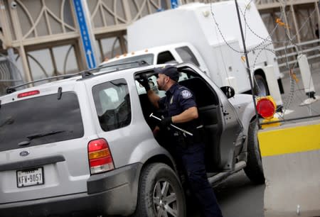 A U.S. Customs and Border Protection officer inspects a particular vehicle on the international border bridge Paso del Norte, as seen from Ciudad Juarez