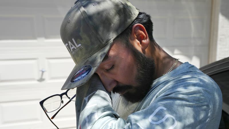 After finishing up an air conditioning repair call, Michael Villa, a service tech with Total Refrigeration, finds shade as he wipes sweat from his face July 19, 2023, in Laveen, Ariz. The massive heat wave in the U.S. is expanding to more regions.