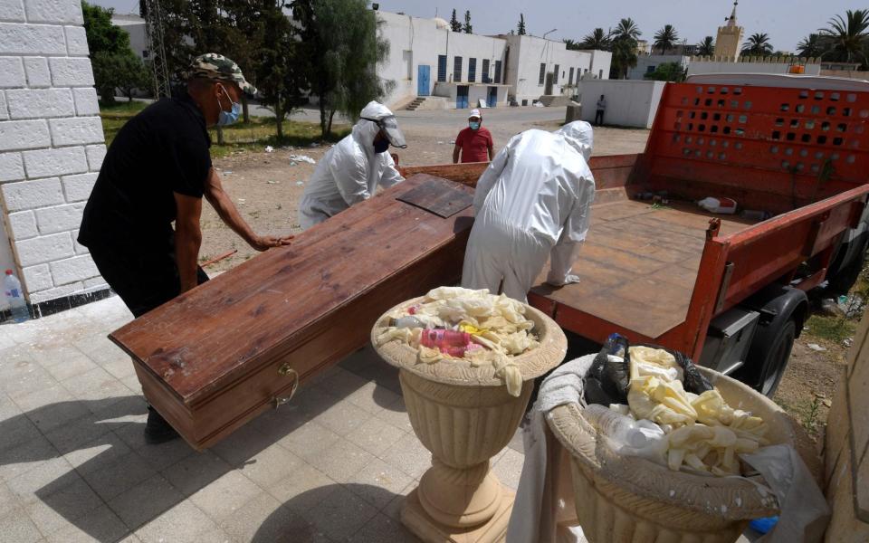 Tunisian officials load the body of a Covid-19 victim onto a truck at the Ibn al-Jazzar hospital in the east-central city of Kairouan - FETHI BELAID/AFP via Getty Images