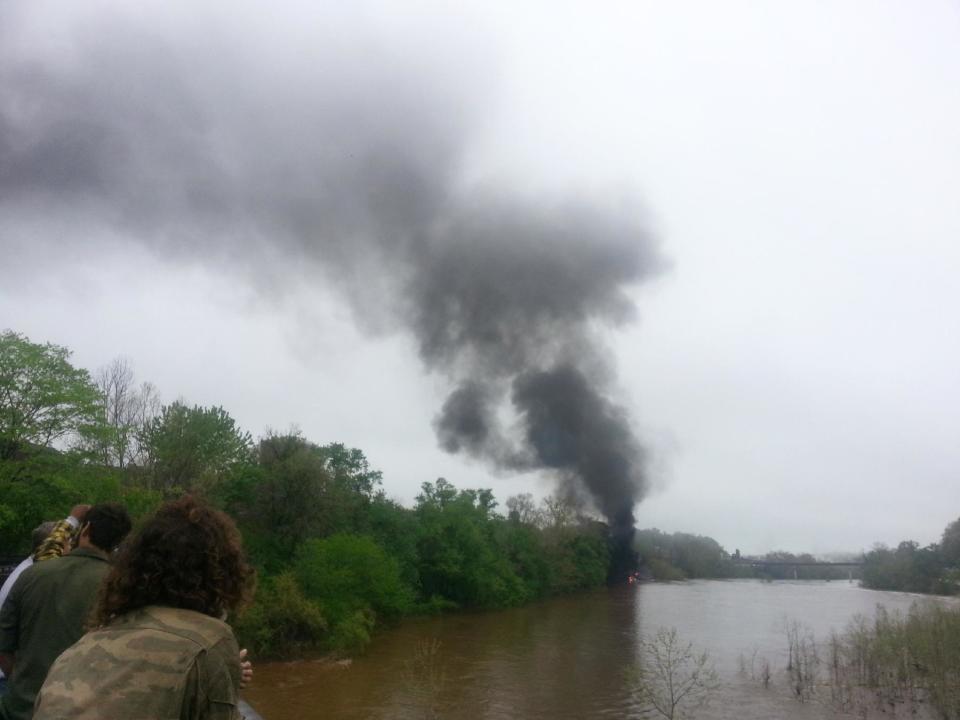 In this mobile phone photo provided Allison Hallock, people watch smoke rise from a bridge over the James river after several CSX tanker cars carrying crude oil derailed, Wednesday, April 30, 2014, in Lynchburg, Va. Authorities evacuated numerous buildings Wednesday after the derailment. (AP Photo/Ali Hallock) MANDATORY CREDIT