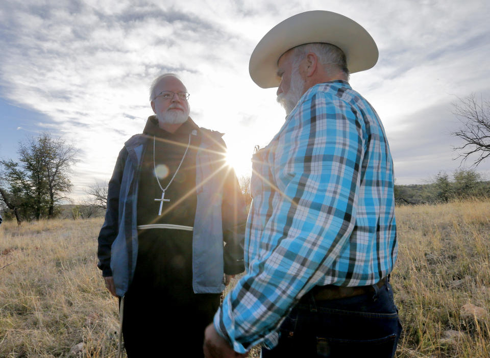 Boston Archdiocese Cardinal Sean O'Malley, left, talks Father Peter Neeley, of Nogales, during a tour of areas used for human smuggling, early Tuesday, April 1, 2014, along the international border in Nogales, Ariz. A delegation of Roman Catholic leaders celebrated Mass along the U.S.-Mexico border to raise awareness about immigration and to pray for policy changes. (AP Photo/Matt York)