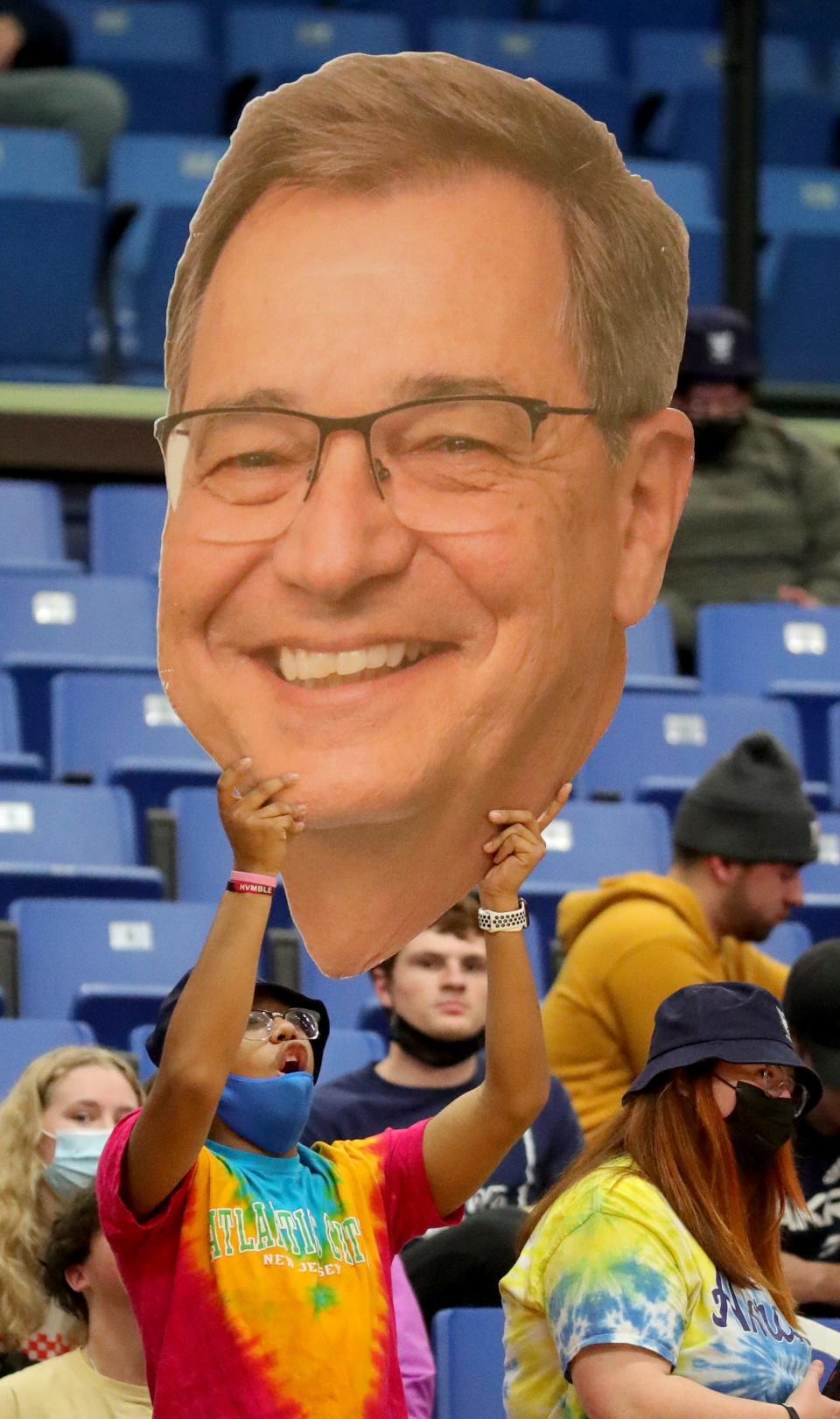 An Akron fan holds up a photo of then-UA President Gary Miller while in the stands in 2022, cheering on the Zips against Bowling Green at the James A. Rhodes Arena in Akron.