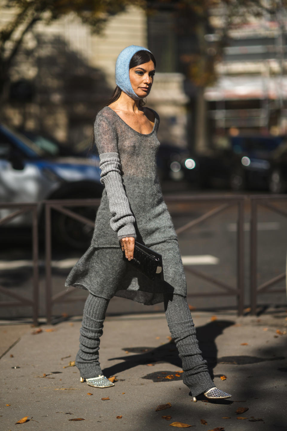 PARIS, FRANCE - OCTOBER 05: Angela Rozas Saiz wears a blue braided wool hood / balaclava, a gray long V-neck t-shirt, a matching long gray skirt, pale gray ribbed wool gloves, a black shiny leather clutch, dark gray ribbed gaiters / socks, white leather mesh with embroidered rhinestones heels sandals / shoes, outside Miu Miu, during Paris Fashion Week - Womenswear Spring Summer 2022, on October 05, 2021 in Paris, France. (Photo by Edward Berthelot/Getty Images)