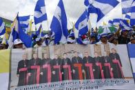 FILE - Anti-government demonstrators hold a banner featuring a group of Catholic cardinals including Nicaraguan Leopoldo Brenes, center right, and a quote from John Paul II that reads in Spanish, "The Church is the first to want peace!", during a march supporting the Catholic Church, in Managua, Nicaragua, July 28, 2018. The Nicaraguan Catholic Church has been sympathetic toward protesters opposed to President Daniel Ortega's government. Ortega has responded by accusing some bishops of being part of a plot to overthrow him and calling them "terrorists." (AP Photo/Alfredo Zuniga, File)