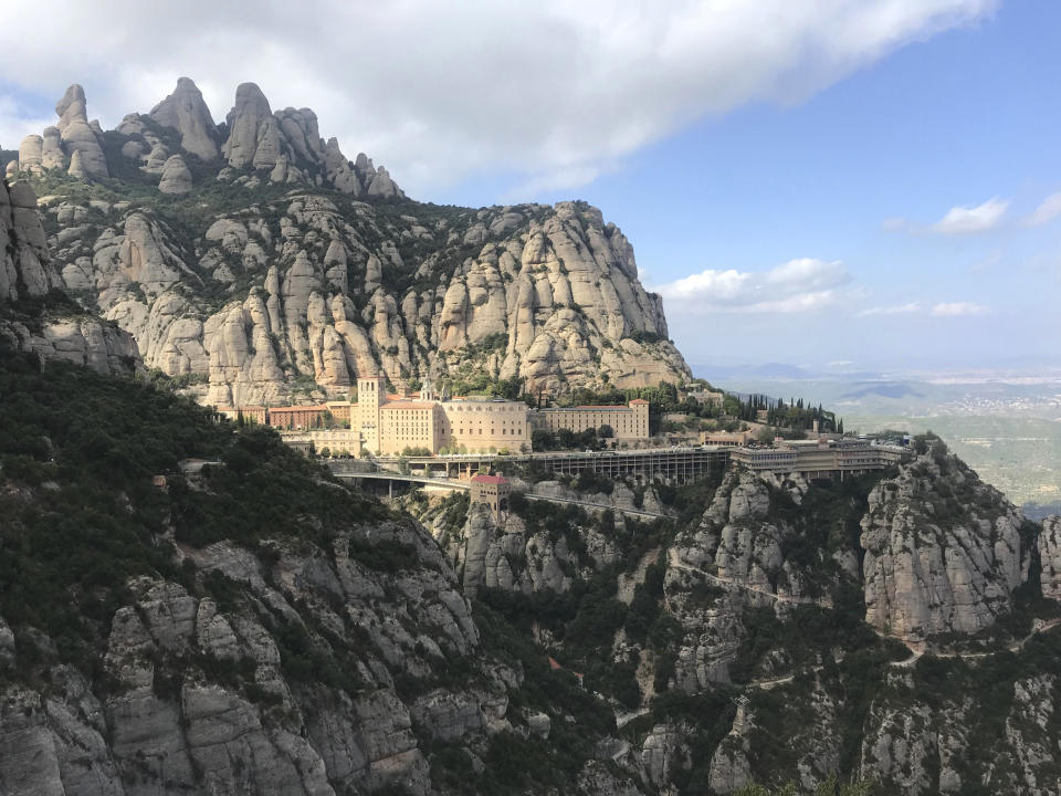 This Oct. 13, 2019 photo shows the mountaintop monastery of Montserrat about an hour’s train ride from Barcelona, Spain. Take the cable car up to Montserrat for 360-degree views of the green valley below and rocky peaks ahead. The church is beautiful, but the mountain was the star. Montserrat boasts lots of walks, including a 3-mile jaunt on a paved path from the top of the peak to a viewpoint overlooking the monastery. (Courtney Bonnell via AP)