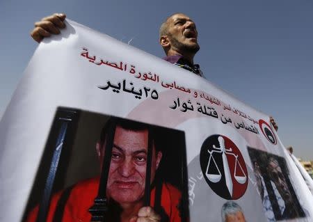 A man whose relatives were killed during the 2011 Egyptian revolution, holds a banner with pictures of former Egyptian President Hosni Mubarak as he shouts slogans outside the police academy on the outskirts of Cairo September 27, 2014. REUTERS/Amr Abdallah Dalsh/Files