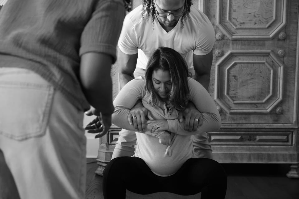 Tahwii Spicer, left, a former doula, instructs her brother, Julius O’Neill, on how to help support his wife, Jessica O’Neill, as they practice positions that aid labor, such as squatting, at her home in Charlotte. (Travis Dove for The Washington Post)