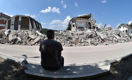 A man sits in front of collapsed houses following the earthquake in Amatrice, central Italy, August 30, 2016. REUTERS/Emiliano Grillotti