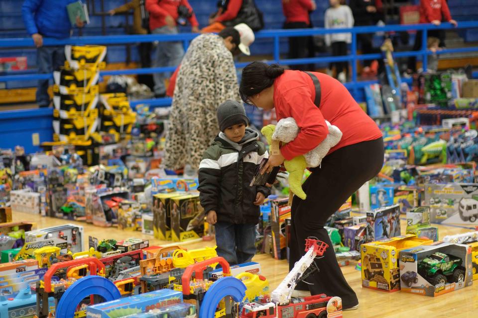 A volunteer helps a child choose a toy Saturday at the 10th annual Northside Toy Drive held at the Palo Duro High School Gym in Amarillo.