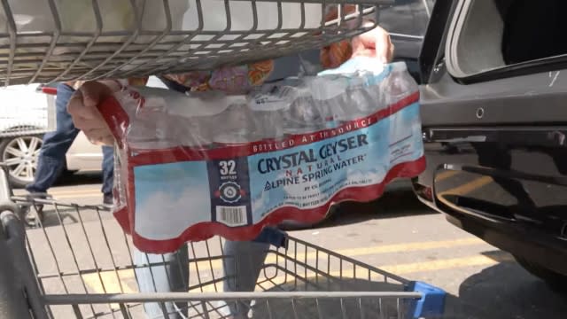 Woman loading a case of water in her cart