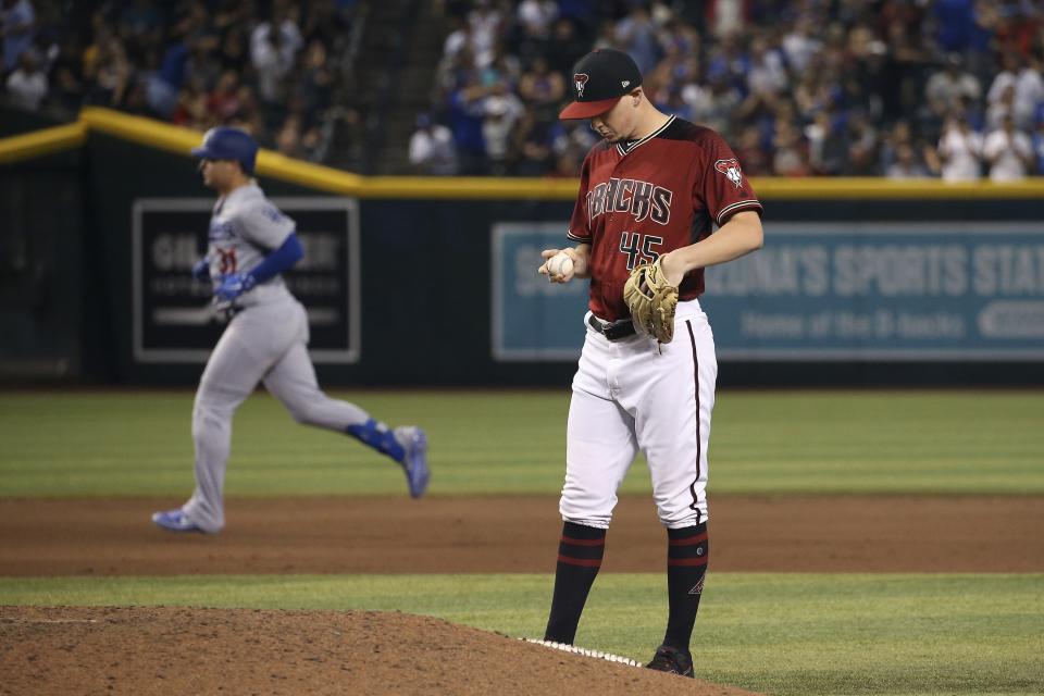 Arizona Diamondbacks relief pitcher Taylor Clarke, right, looks at a new baseball after giving up a home run against Los Angeles Dodgers' Joc Pederson, left, during the 11th inning of a baseball game Sunday, Sept. 1, 2019, in Phoenix. The Dodgers defeated the Diamondbacks 4-3. (AP Photo/Ross D. Franklin)