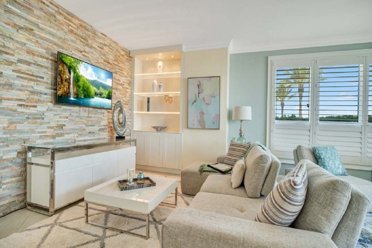 Plantation shutters, a stone feature wall and crown molding frame this first-floor, marina-front home, featuring an expanded patio that is the "go-to spot" for peaceful outdoor lounging.