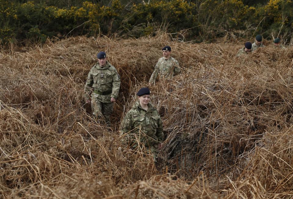 British army officers walk on a WW1 practise trench as they pose for the photographers in Gosport, southern England, Thursday, March 6, 2014. This overgrown and oddly corrugated patch of heathland on England’s south coast was once a practice battlefield, complete with trenches, weapons and barbed wire. Thousands of troops trained here to take on the Germany army. After the 1918 victory _ which cost 1 million Britons their lives _ the site was forgotten, until it was recently rediscovered by a local official with an interest in military history. Now the trenches are being used to reveal how the Great War transformed Britain _ physically as well as socially. As living memories of the conflict fade, historians hope these physical traces can help preserve the story of the war for future generations. (AP Photo/Lefteris Pitarakis)