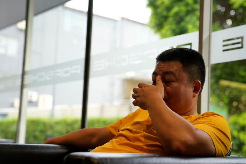 Guo Hui reacts as he waits at a car dealership to sell his Porsche Cayenne in order to pay his debts, in Guangzhou