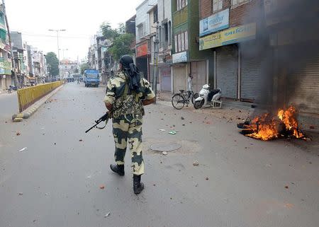 A police officer patrols a deserted road after a clash in Vadodara in the western Indian state of Gujarat September 26, 2014. REUTERS/Stringer