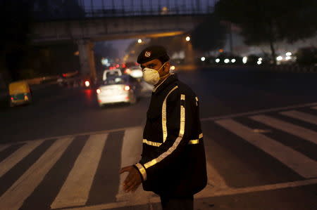 A traffic policeman wears a mask to protect himself from dust and air pollution as he signals to drivers in New Delhi, India, December 23, 2015. REUTERS/Adnan Abidi